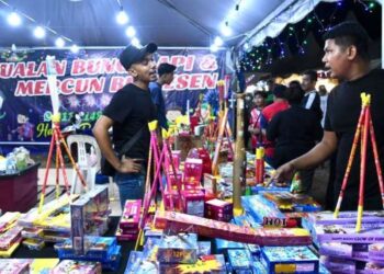 SEORANG penjual melayani pelanggan yang singgah di gerainya untuk membeli mercun dan bunga api di Festival Mega Raya Aidilfitri di Kangar Jaya, Perlis, semalam. – FOTO/IZLIZAN OTHMAN