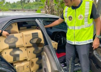 ANGGOTA penguat kuasa KPDNHEP Kelantan memeriksa Proton Wira Aeroback yang sarat dengan 1,020 kilogram minyak masak peket di Jalan Hulu Stesen Kereta Api Wakaf Bharu, Tumpat, Kelantan, semalam. -IHSAN KPDNHEP KELANTAN