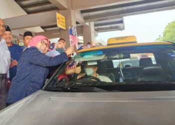 KALSOM Nordin (kanan) melekatkan Jalur Gemilang pada sebuah teksi ketika Majlis Pra Pelancaran Jalur Gemilang di Melaka Sentral, Peringgit, Melaka. - FOTO/MUHAMMAD SHAHIZAM TAZALI