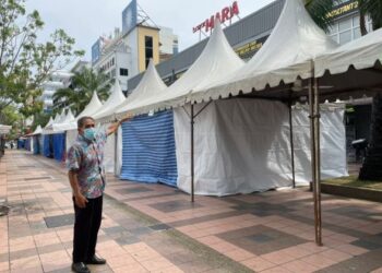 SHEIKH Abdul Aziz Sheikh Abdul Rahman menunjukkan kedainya yang terlindung di belakang khemah bazar Aidilfitri di Jalan Hang Tuah, Melaka, semalam. - FOTO/DIYANATUL ATIQAH ZAKARYA