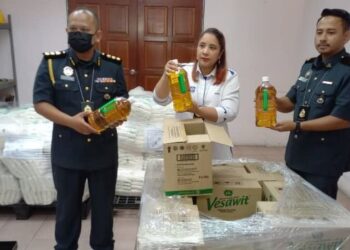 NORENA Jaafar menunjukkan minyak masak botol yang dirampas KPDNHEP dalam satu serbuan di sebuah stor penyimpanan di Ayer Keroh, Melaka. - FOTO/AMRAN MULUP