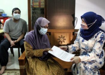 RINA Mohd. Harun (kanan) menyerahkan surat kelulusan bantuan kanak-kanak JKM kepada Narriman Husin, 56, (tengah) ketika lawatan ihsan di Jalan Cheng Lama, Taman Cheng Permai, Melaka, hari ini. - FOTO/RASUL AZLI SAMAD