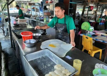 SEORANG penebar roti canai menyiapkan hidangan roti telur di Warung Beca Pokok Mangga, Melaka. - UTUSAN/AMRAN MULUP