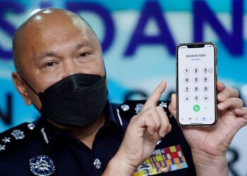 MOHD. Kamarudin Md. Din menunjukkan nombor telefon CCID Scam Response Center dalam sidang akhbar di JSJK Bukit Aman di Menara KPJ Kuala Lumpur, semalam. UTUSAN/FAUZI BAHARUDIN