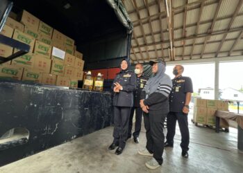 SURINA Saad (kiri) meninjau kotak minyak masak yang dirampas dalam operasi dilaksanakan di Kampung Baru Padang Besar, Perlis hari ini. - UTUSAN/ASYRAF MUHAMMAD