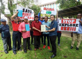 MAHADZIR Abdul Hamid (baju merah) menyerahkan memorandum berhubung kecurian dan salah guna kuasa Kerajaan Negeri Kedah berkaitan REE kepada Chan Ming Kai di luar Bangunan Perdana Putra, Putrajaya. - UTUSAN/FAISOL MUSTAFA