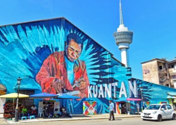 SEORANG pemuda berjalan di hadapan lukisan mural tukang kasut yang mana kawasan itu lokasi mereka mencari makan sejak era 80-an di Jalan Mahkota, Kuantan, Pahang. - UTUSAN/SHAIKH AHMAD RAZIF