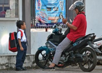 Gelagat seorang bapa yang merakam gambar anaknya sebelum menyertai  orientasi murid Tahun 1 di Sekolah Kebangsaan Danau Kota, Setapak di Kuala Lumpur semalam. – UTUSAN/SYAKIR RADIN