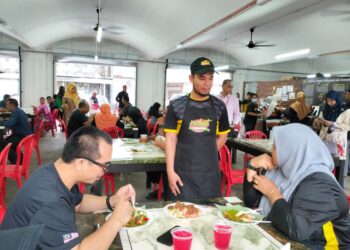 SHAZLAN Taieffu Azlan (tengah) menyantuni pelanggan sempena program hidangan percuma sempena sambutan Ramadan di Restoran Nasi Dagang Atas Tol cawangan Bandar, Kuala Terengganu, hari ini. - UTUSAN/AKAMALIZA KAMARUDDIN/