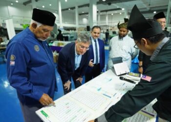 PENGUNJUNG tidak melepaskan peluang menyaksikan sendiri proses percetakan al-Quran di Nasyrul Quran, Putrajaya. - UTUSAN/AMREE AHMAD