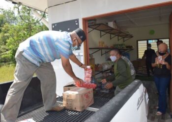 AHMAD NAZLAN Idris membantu menurunkan barang keperluan dapur di pusat pengumpulan Kampung Kuala Tahan, Jerantut, Pahang. - UTUSAN/HARIS FADILAH AHMAD
