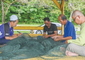 SEKUMPULAN nelayan mengisi masa lapang dengan menjahit pukat selepas tidak dapat keluar menangkap ikan  pada musim tengkujuh di Kampung Seberang Marang, Marang. – UTUSAN/PUQTRA HAIRRY ROSLI