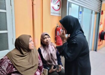 Ruslina Taslim (kanan) ditenangkan oleh ahli keluarganya ketika menuntut jenazah suaminya Abd. Rashid Abd.  Malek di rumah mayat Hospital Pontian, di Pontian, malam kelmarin.