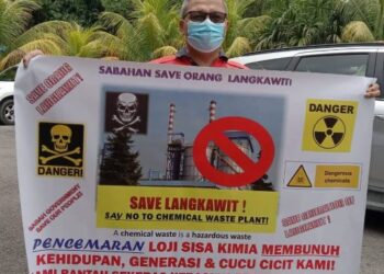 Wakil penduduk Jupiri Apou menunjukkan kain rentang bantahan pembinaan loji sisa kimia di Kampung Langkawit, Papar