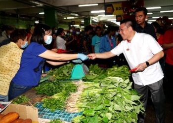 NGA Kor Ming (kanan) menyampaikan angpau kepada peniaga pada program walkabout di Pasar Besar Ipoh hari ini. - UTUSAN/ZULFACHRI ZULKIFLI