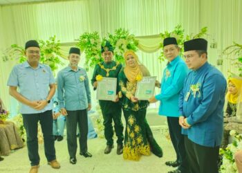 AMINUDDIN Harun (dua dari kanan) menyerahkan sijil dan kad pernikahan pasangan suami isteri, Badrul Hisham Kasim dan Murshiah Yidin pada Majlis Penyerahan Kompleks JHEAINS Kuala Pilah hari ini.-UTUSAN/NOR AINNA HAMZAH