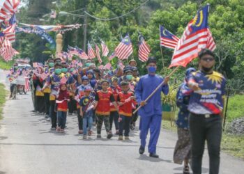 SEBAHAGIAN penduduk Kampung Nongka yang terdiri daripada pelbagai lapisan umur menyertai perarakan sempena Hari Kemerdekaan dengan berarak mengelilingi kampung sambil mengibarkan Jalur Gemilang di Kubang Pasu, di sini. -UTUSAN/ SHAHIR NOORDIN