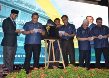 AMINUDDIN Harun (dua dari kiri) melihat Direktori Usahawan Kotej Halal Negeri Sembilan pada Majlis Penyampaian Sijil Pengesahan Halal Malaysia dan Ramah Mesra Menteri Besar Bersama Usahawan Kotej Halal Negeri Sembilan di Seremban, semalam.-UTUSAN/ZAKKINA WATI AHMAD TARMIZI