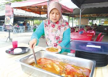 SITI Noerjanah menyediakan hidangan Menu Rahmah berharga RM5 yang ditawarkan di Warung Jannah, Rasah, Seremban, Negeri Sembilan. - UTUSAN/ZAKKINA WATI AHMAD TARMIZI