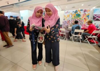 NUR Aina Najla' Md Azan (kiri) dan adik kembarnya, Nur Aina Amirah melihat risalah promosi program-program pendidikan ketika hadir ke Karnival Institusi Pendidikan Mara (Kipma) 2022 Peringkat Negeri Sembilan dan Melaka yang diadakan di Seremban 2, Seremban hari ini. - FOTO/BADRUL HAFIZAN MAT ISA