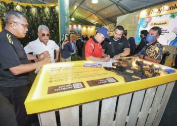 ABD. Razak Kamardin (kiri) beramah mesra dengan pengunjung yang mendaftar di kiosk Maybank pada penganjuran MSAM 2022 di Port Dickson, Negeri Sembilan.-MINGGUAN/MOHD. SHAHJEHAN MAAMIN