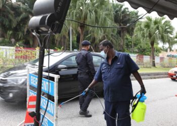 SEORANG petugas MBSA melakukan kerja sanitasi di lokasi sekatan jalan raya di Shah Alam, semalam. - UTUSAN/ABDUL RAZAK IDRIS