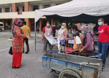 ABDUL Rahman Said dan Zaleha Mohamad menaiki motosikal roda tiga untuk mendapatkan suntikan vaksin di PPV Sekolah Kebangsaan Tunjang, Jitra, Kubang Pasu semalam. -UTUSAN/ ZAID MOHD NOOR