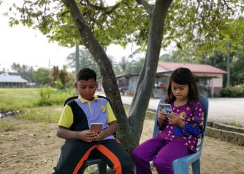 Murid Orang Asli, Nurallisyazana Abdullah, 10, dan Nazirul Badrul, 11, mengikuti pembelajaran PdPR menggunakan telefon bimbit 
di Kampung Redang Punggor, Chenderong Balai dekat Pasir Salak.
– UTUSAN/AIN SAFRE BIDIN