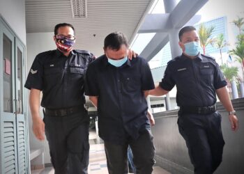 IDILHAN Ibrahim (tengah) dikawal anggota polis selepas didakwa memiliki senjata sukan paintball yang menyerupai senjata tiruan di Mahkamah Majistret, Ayer Keroh, Melaka, hari ini. UTUSAN/RASUL AZLI SAMAD