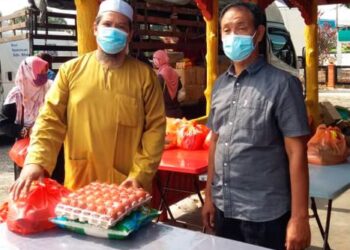SIDEK Tamsir (kanan) menyampaikan bakul makanan kepada ahli-ahli Persatuan Pasar Malam Pontian yang terjejas ekoran sekatan pergerakan penuh di Pontian, Johor. - UTUSAN/MUHAMMAD ZIKRI