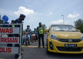 ROHAIMI Md. Isa memeriksa sebuah kenderaan yang melalui sekatan jalan raya (SJR) Kuala Dungun di Dungun hari ini.- UTUSAN/PUQTRA HAIRRY ROSLI