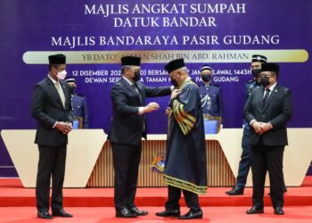 HASNI Mohammad (dua kiri) memakaikan pakaian istiadat kepada Asman Shah Abd. Rahman pada Majlis Angkat Sumpah Datuk Bandar MBPG yang pertama di Dewan Muafakat Taman Mawar, Pasir Gudang, Johor.
