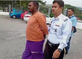ANGGOTA polis mengiringi P. Yuaraj (kiri) bagi menghadapi pertuduhan memandu cuai di Mahkamah Majistret Slim River hari ini. - UTUSAN