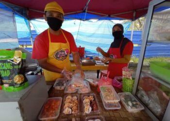 MUHAMAD Lutfi Mohamad Supian (kiri) dan isterinya, Nguyen Fatimah Abdullah kini berniaga makanan demi kelangsungan hidup selepas diberhentikan kerja ekoran pandemik Covid-19 tahun lalu di Bandar Penawar, Kota Tinggi di Johor. -UTUSAN/MASTURAH SURADI