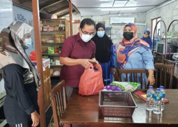 Baharuddin (tengah) membantu mengagihkan barang keperluan asas daripada Gerobok Prihatin kepada penduduk yang memerlukan di Rumah Pangsa Taman Air Biru, Pasir Gudang, hari ini.