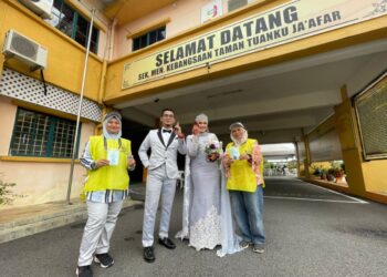 SHAH Eskandar Abd. Ghafar Azmi dan Nurul Amirah Anuar berbusana pengantin ketika mengundi di pusat pengundian Sekolah Menengah Kebangsaan (SMK) Taman Tuanku Jaafar, Seremban, Negeri Sembilan. -UTUSAN/AFIFI HAFIZ MOHD. NOR