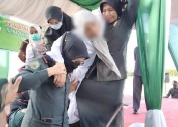 WANITA yang pengsan selepas menjalani hukuman sebat 100 kali setelah didapati bersalah melakukan janayah zina dipapah untuk mendapatkan rawatan di Lhoksuemawe, Aceh hari ini. - Gambar Tribunenews.