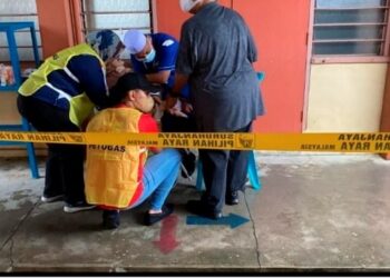 PETUGAS SPR dan orang ramai membantu seorang wanita yang mengalami sesak nafas sebelum disahkan meninggal dunia selepas mengundi di SMK Sultan Ismail, Johor Bahru.