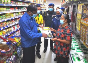 S. Veerapan (kiri) menyampaikan risalah SHMMP Deepavali 2021 kepada pelanggan di sebuah pasar raya di Senawang, Negeri Sembilan hari ini sambil diperhatikan Ain Arjuna Aziz Zaman (dua dari kanan). - UTUSAN/AFIFI HAFIZ MOHD. NOR