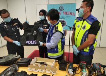 OTHMAN Nanyan (tengah) memeriksa baju kalis peluru seorang anggota polis yang terkena tembakan penjenayah warga asing dalam sidang akhbar di Temerloh, Pahang, semalam.