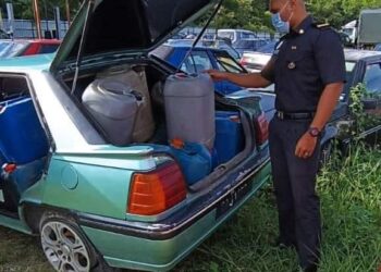 ANGGOTA KPDNHEP Kelantan memeriksa minyak diesel yang dirampas selepas menahan sebuah kereta di Simpangan, Tumpat, Kelantan. - IHSAN KPDNHEP KELANTAN