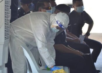SEORANG petugas kesihatan dipercayai dari Jabatan Kesihatan melakukan proses sanitasi pada kerusi pengundi ketika pengundian awal PRK DUN Slim di IPD Muallim, Tanjung Malim hari ini. - FOTO/ZULFACHRI ZULKIFLI