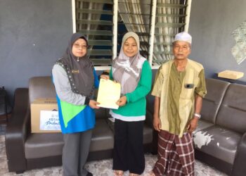FARIHAH  Che Husin (kiri) menyerahkan faedah pengurusan jenazah kepada Nur Farahah Shahdan di Kampung Pengkalan Batu, Kuala Nerus, Terengganu, semalam. - UTUSAN/TENGKU DANISH BAHRI TENGKU YUSOFF