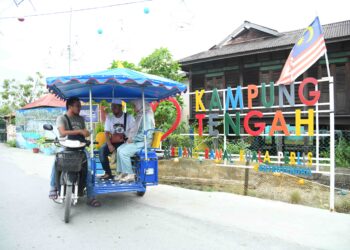 NUR Afiq Nasharudin, 26, membawa pengunjung menaiki tuk tuk bagi menikmati keindahan perkampungan nelayan di tapak Program Transformasi Diraja Kampung Nelayan Warna-Warni Seberang Ramai Kuala Perlis.- UTUSAN/IZLIZAN OTHMAN