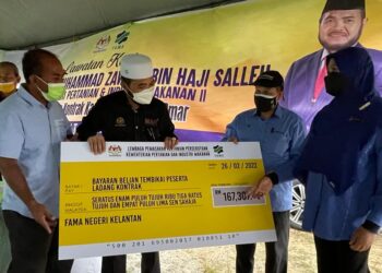 NIK Muhammad Zawawi Salleh (dua dari kiri) menyerahkan bayaran tanaman tembikai kepada peserta ladang kontrak di Kampung Haji Wan Omar, Pasir Puteh, hari ini - UTUSAN/TOREK SULONG