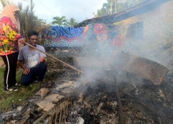 MOHAMAD Faridzul Azahar Abd. Wahab dan pasangannya, Nur Nadhirah Ahmad Akbal membakar peralatan rumah termasuk barang persiapan majlis perkahwinan mereka yang rosak ditenggelami banjir di Kampung Pianggu, Rompin. – FOTO/SHAIKH AHMAD RAZIF