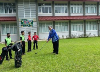 ABD. MANAF Mat (kanan) memukul bola golf sambil diperhatikan muridnya di SK Kampung Bantal, Ulu Tembeling, Jerantut, Pahang. - UTUSAN/HARIS FADILAH AHMAD