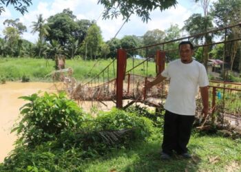 MOHD. FIRDAUS Abdul Razak menunjukkan jambatan gantung Kampung Mambang Berulang yang rosak dan belum diperbaiki selepas banjir melanda Disember tahun lalu di Mentakab, Temerloh, Pahang. - UTUSAN/SALEHUDIN MAT RASAD