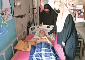 NOOR Ain Momin (berdiri, kanan) dan Noor Azlina menguruskan kebajikan Muhammad Ridwan akibat penyakit ketumbuhan otak di Felda Kota Gelanggi Dua di Jerantut, Pahang. - UTUSAN/HARIS FADILAH AHMAD