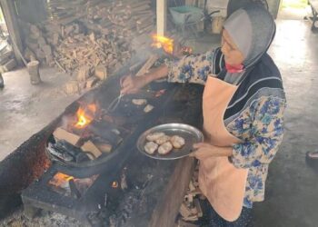 KHATIJAH Ali memilih membakar kuih bakar, akok dan bingka dengan cara tradisional iaitu menggunakan arang di Kampung Balok Baru, Kuantan, Pahang. - UTUSAN/ DIANA SURYA ABD WAHAB